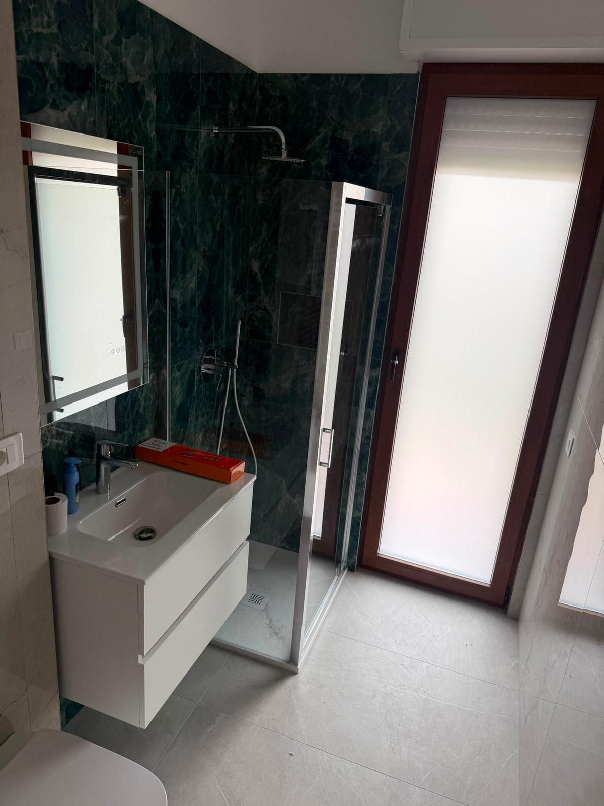 Bagno con mobile lavabo chiaro e doccia scura