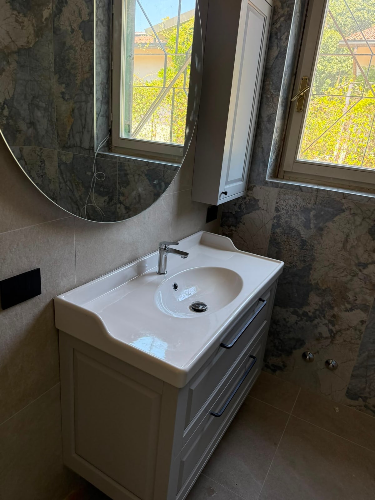 Mobile lavabo con specchio rotondo in un bagno completato